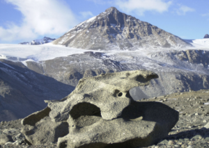 very large rock looks as though an artist designed its odd shape. It sits in front of a beautiful mountain peak in background